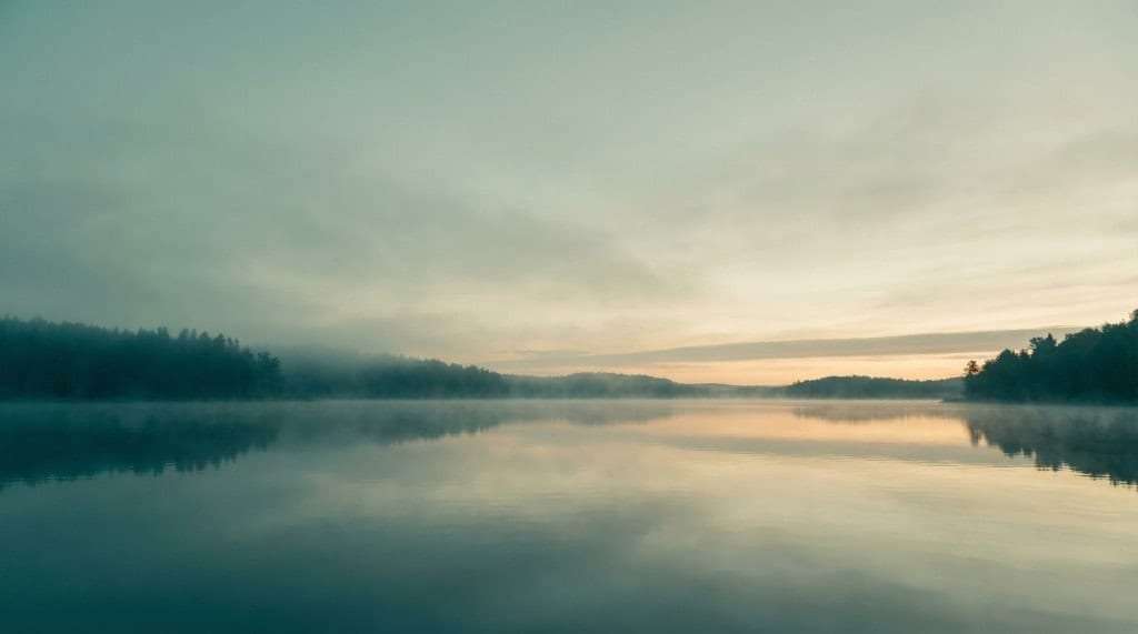 Stiller See in der Dämmerung, spiegelnde Wasserfläche und gedämpfte Farben